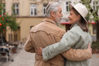 Photo of Affectionate senior couple walking outdoors, back view. Space for text