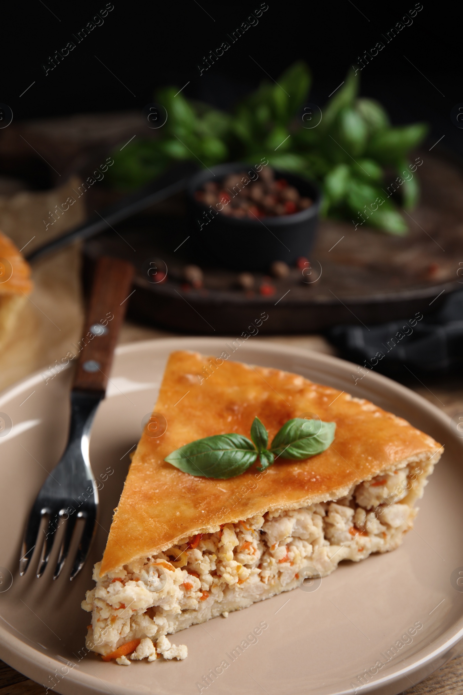 Photo of Piece of delicious pie with meat and basil on wooden table