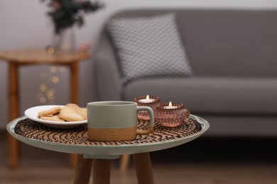 Cup of drink, cookies and burning candles on coffee table indoors. Space for text