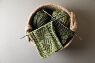 Photo of Green knitting, needles and soft yarns on light background, top view