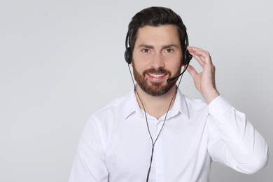 Hotline operator with headset on light grey background, space for text