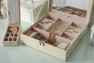 Photo of Jewelry boxes with stylish golden bijouterie on white dressing table