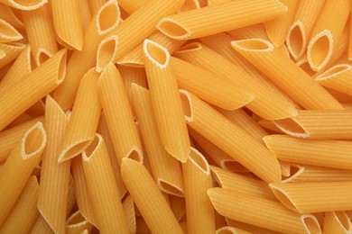 Photo of Uncooked penne pasta as background, top view