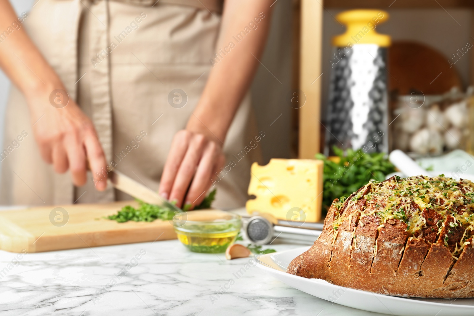 Photo of Tasty homemade garlic bread with cheese  and blurred woman on background. Space for text