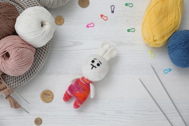 Photo of Crocheted bunny and knitting supplies on white wooden table, flat lay. Engaging in hobby