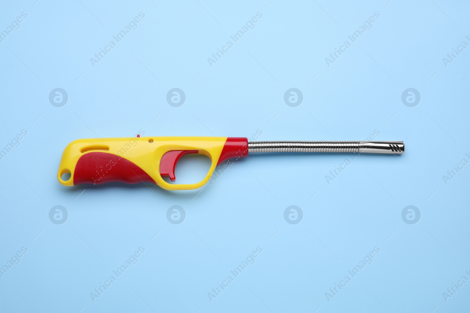 Photo of One gas lighter on light blue background, top view