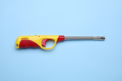 Photo of One gas lighter on light blue background, top view