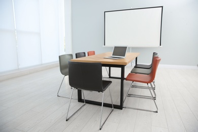 Conference room interior with wooden table and video projection screen