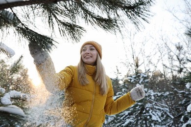 Photo of Woman shaking off snow from tree branch in forest on winter day