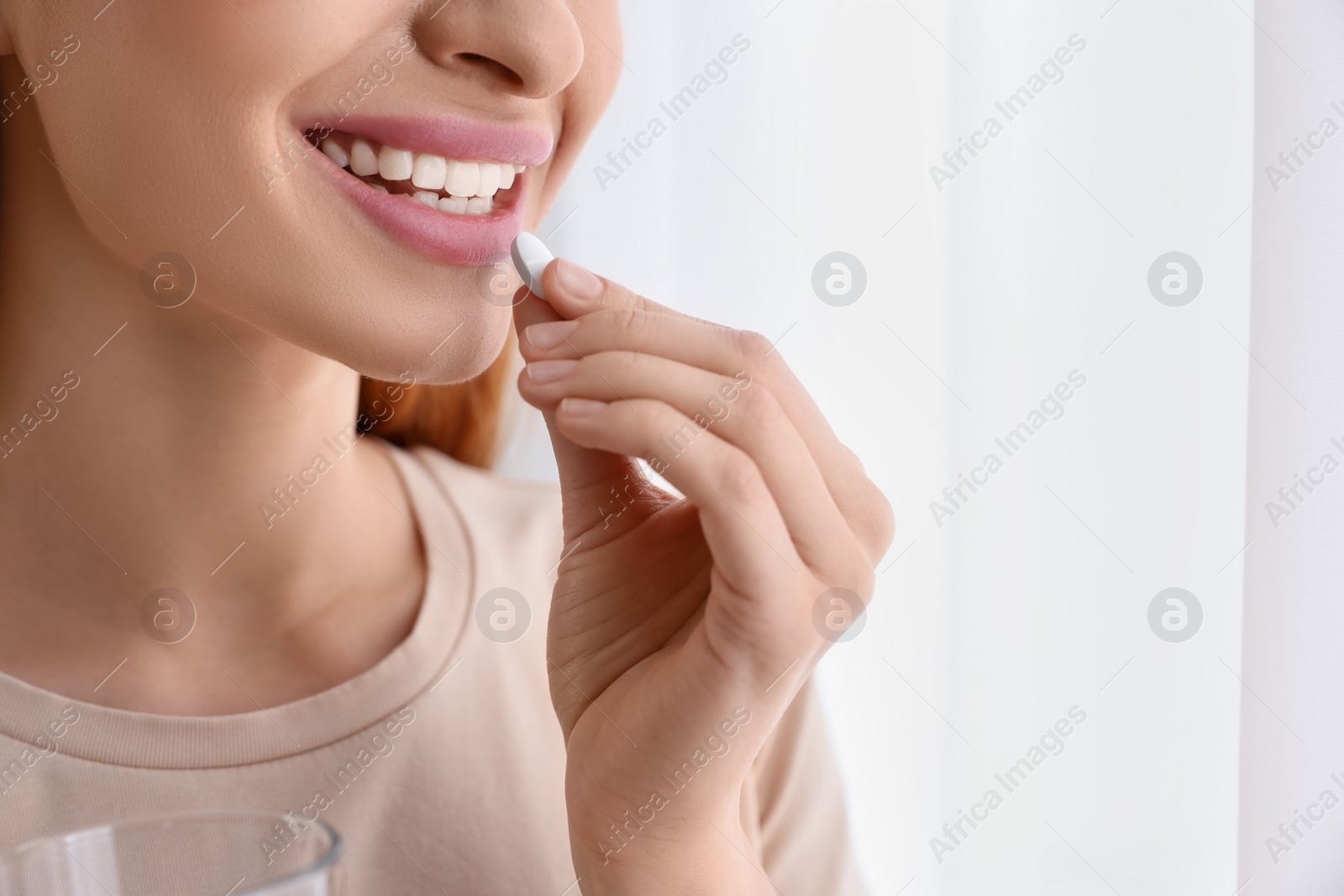 Photo of Young woman taking vitamin pill at home, closeup