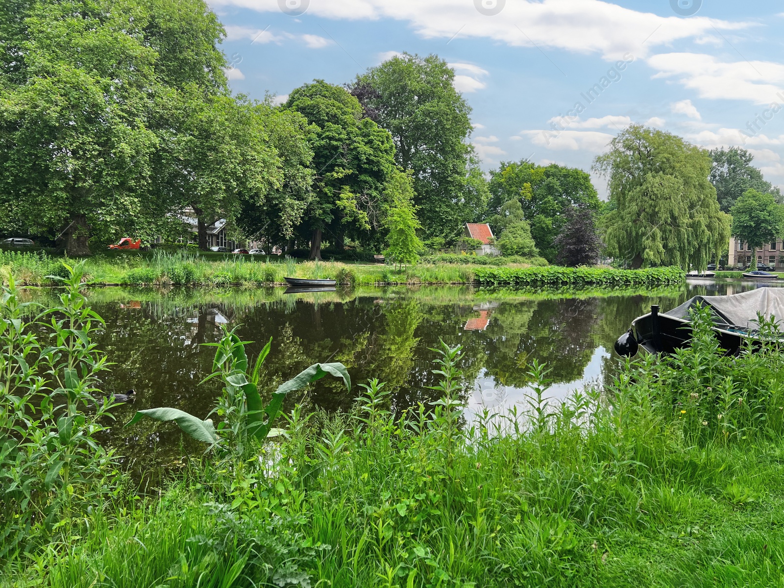 Photo of Beautiful view of city canal with moored boats surrounded by greenery