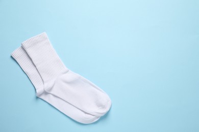 Photo of Pair of white socks on light blue background, flat lay. Space for text