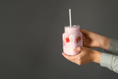 Woman holding fig smoothie on grey background, closeup. Space for text