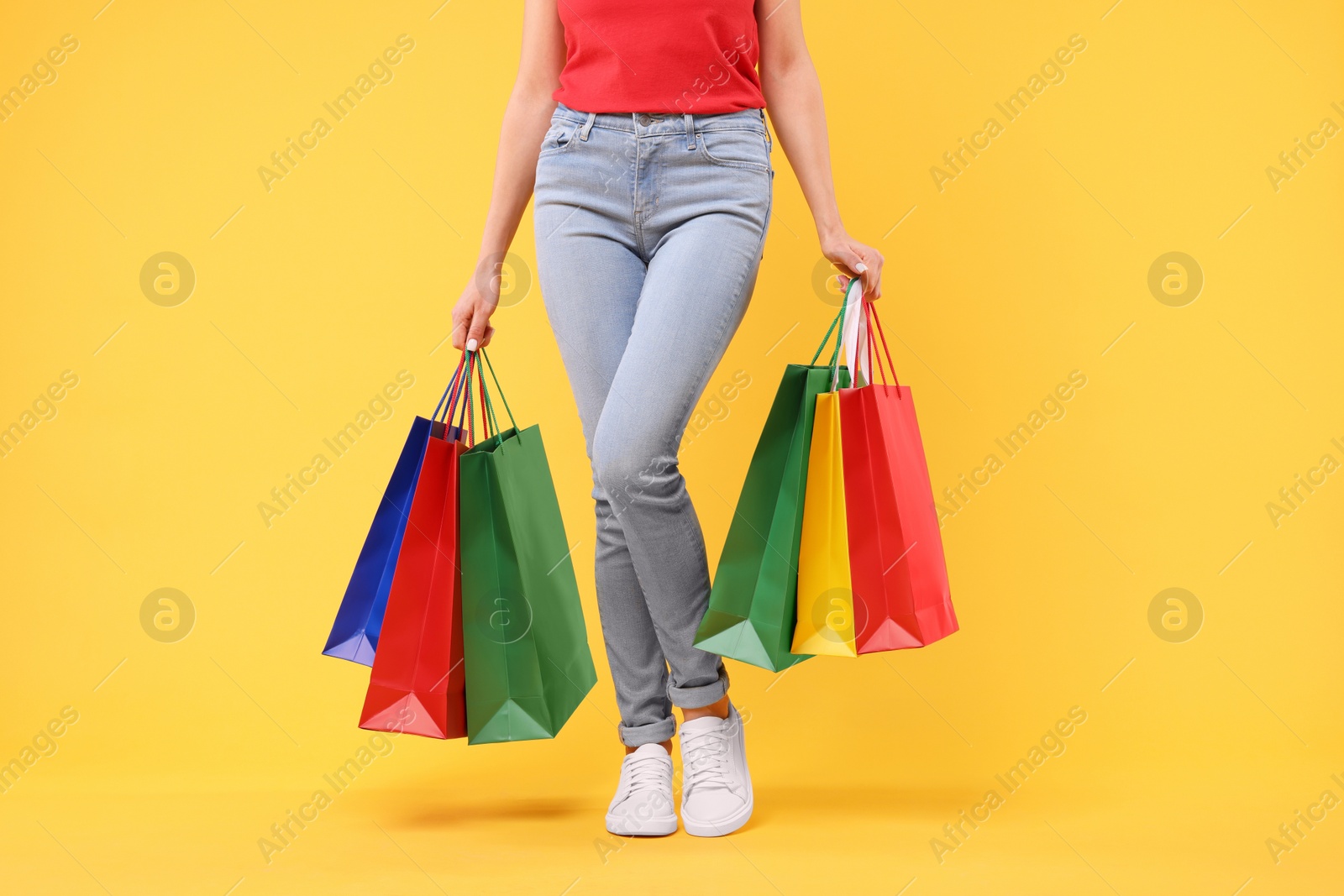 Photo of Woman with shopping bags on yellow background, closeup