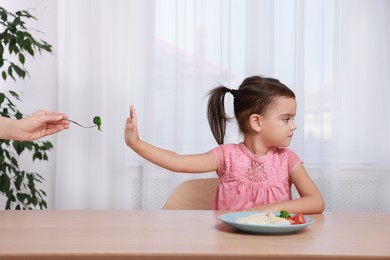 Cute little girl refusing to eat her breakfast at home