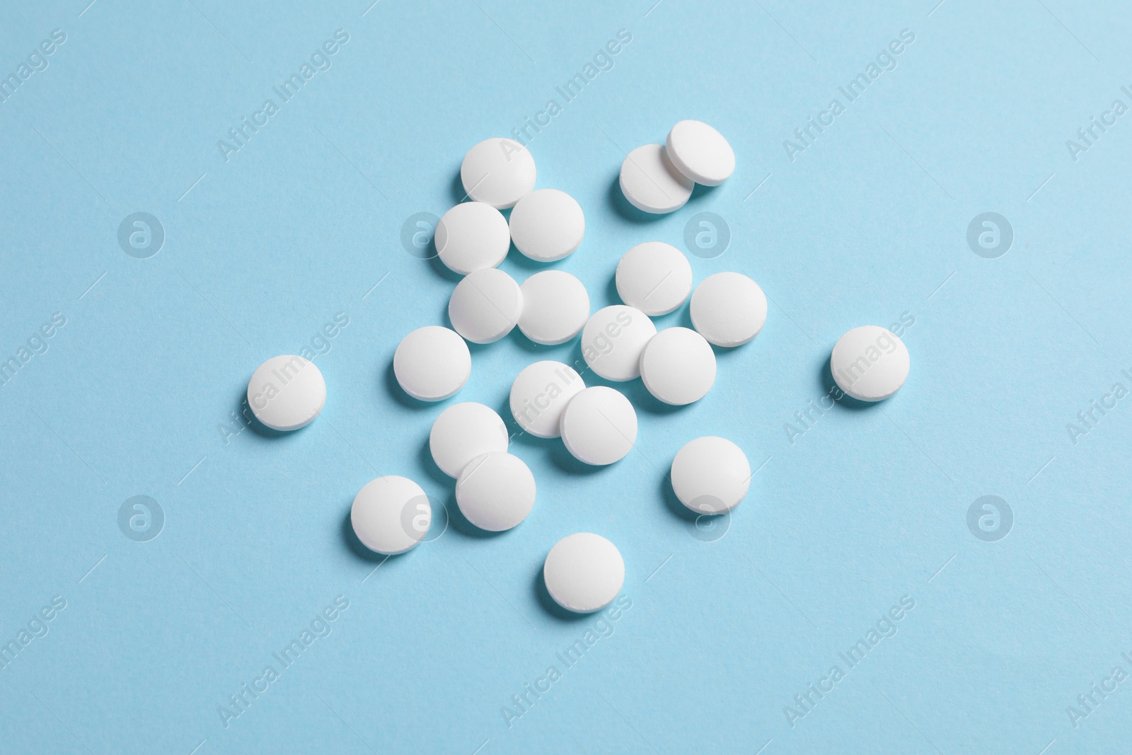 Photo of Many white pills on light blue background, flat lay