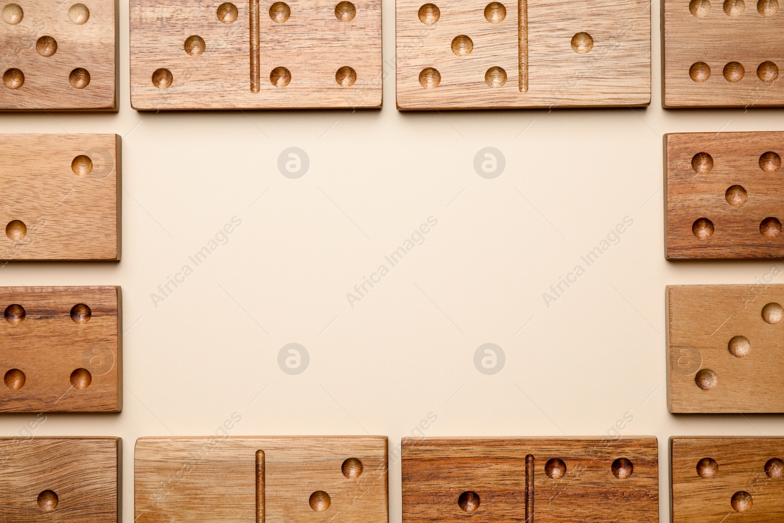 Photo of Frame of wooden domino tiles on beige background, flat lay. Space for text