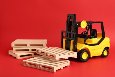Photo of Toy forklift and wooden pallets on red background