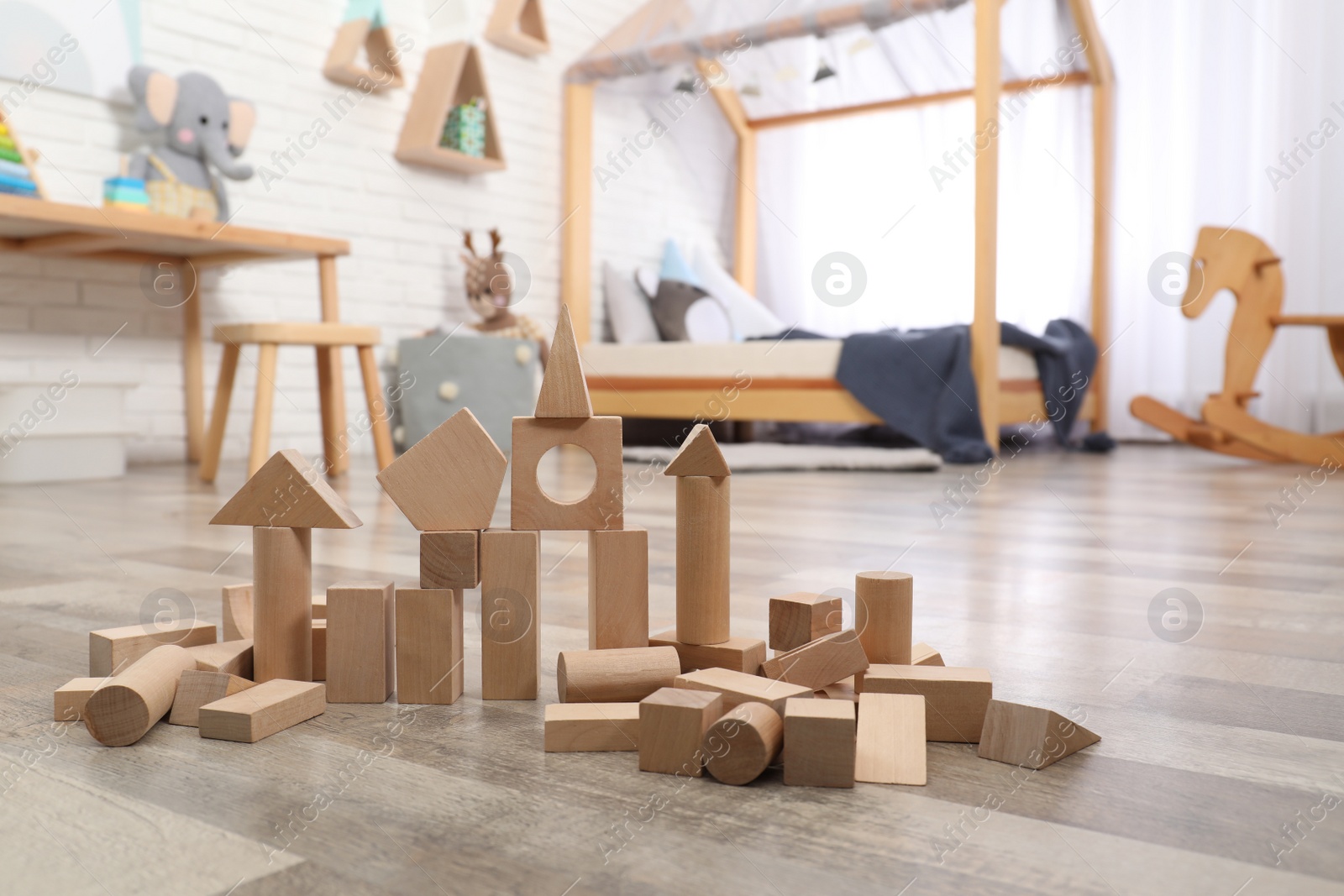 Photo of Wooden toy construction set on floor in playroom. Interior design