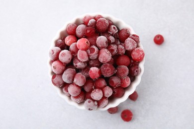 Photo of Frozen red cranberries in bowl on light table, top view