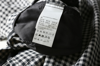Photo of Clothing label with size and care instructions on checkered garment, closeup