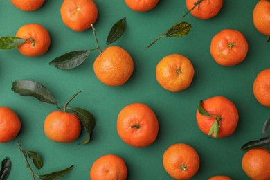 Photo of Fresh ripe tangerines with leaves on green background, flat lay