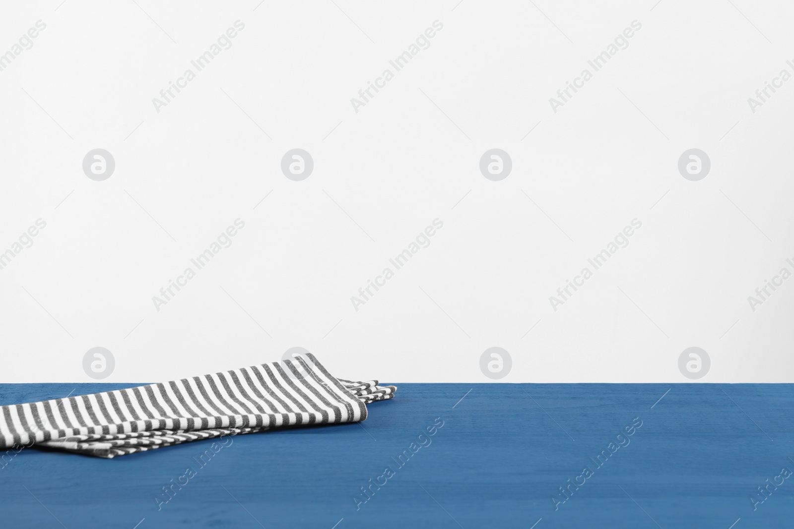 Photo of Napkin on blue wooden table against white background. Space for text