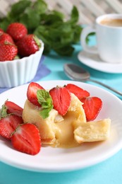 Photo of Tasty vanilla fondant with white chocolate and strawberries on light blue table, closeup