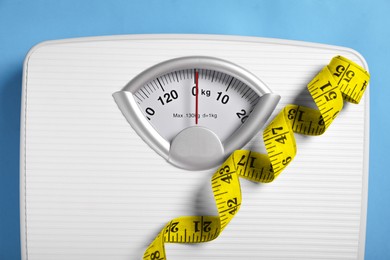 Weight loss concept. Scales and measuring tape on blue background, closeup