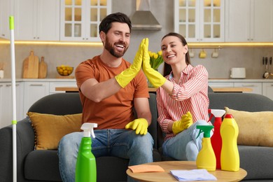 Photo of Spring cleaning. Lovely couple giving high five in living room