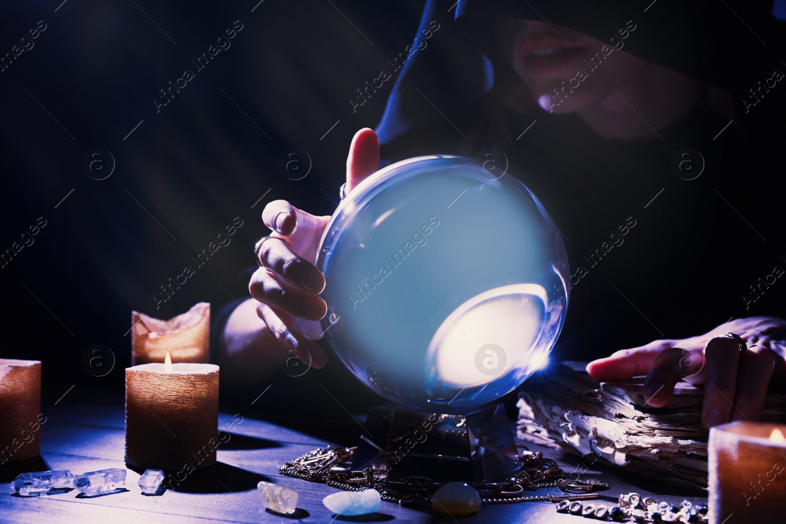 Photo of Soothsayer using crystal ball to predict future at table in darkness, closeup. Fortune telling