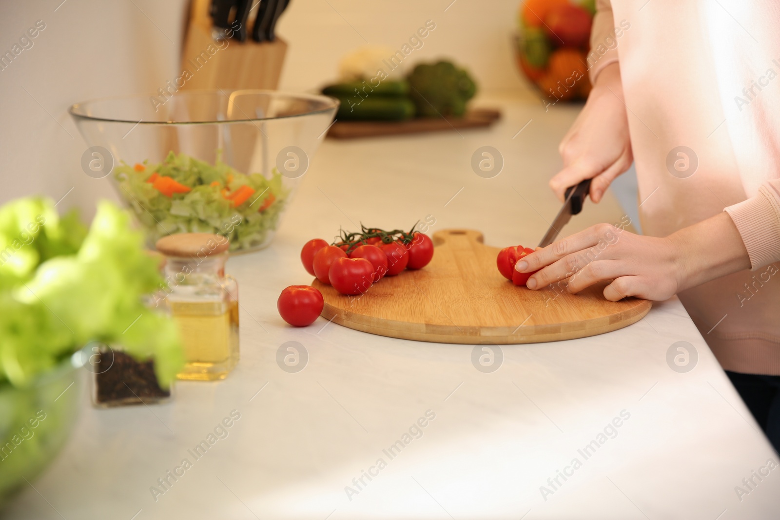 Photo of Young woman cooking at table in kitchen, closeup