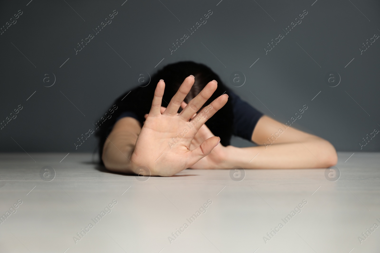 Photo of Young woman making stop gesture while lying on floor indoors