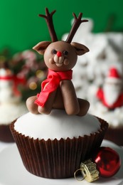 Tasty cupcake with Christmas reindeer figure on table, closeup