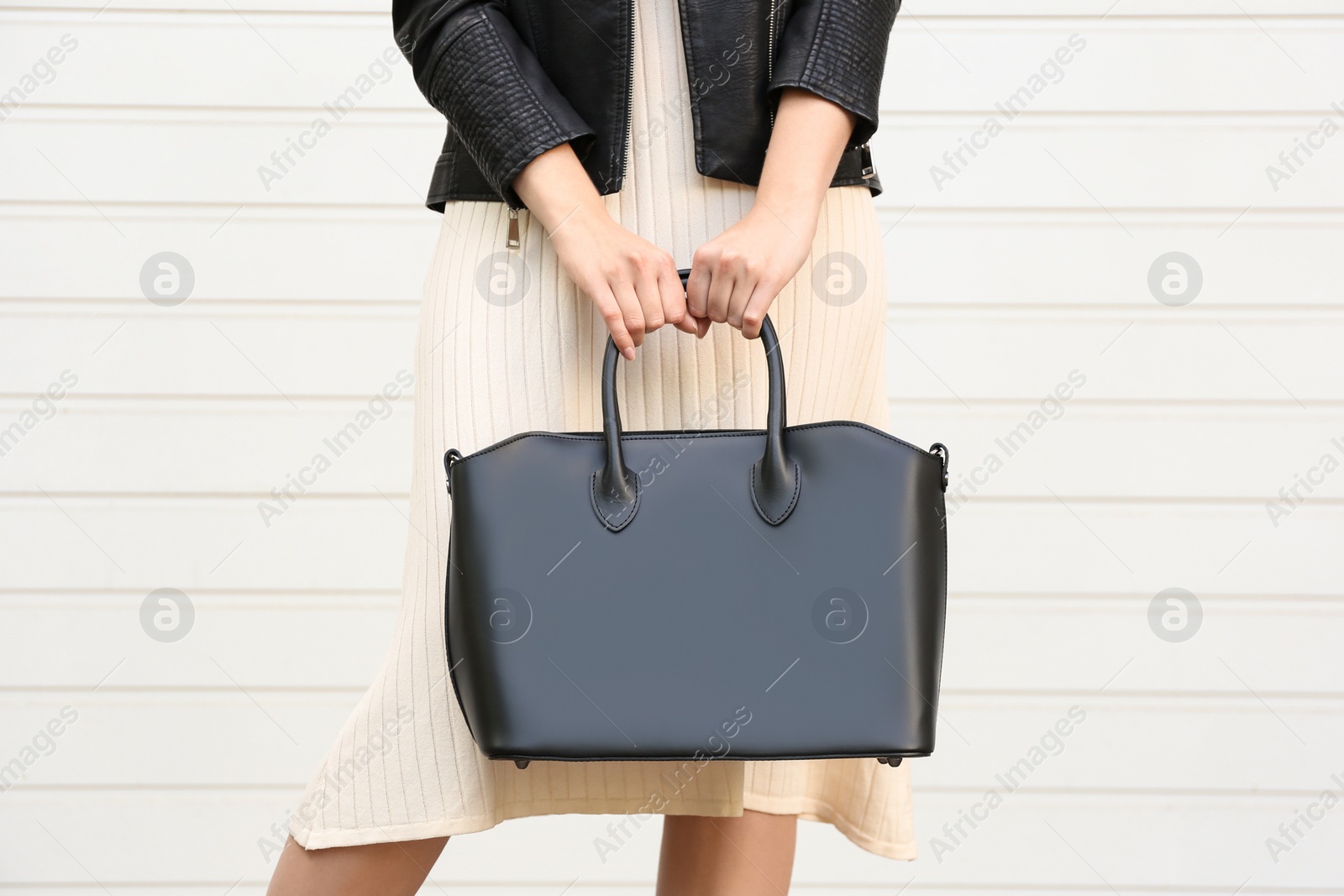 Photo of Young woman with stylish leather bag near white wall, closeup