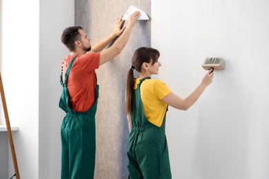 Workers hanging stylish gray wallpaper in room