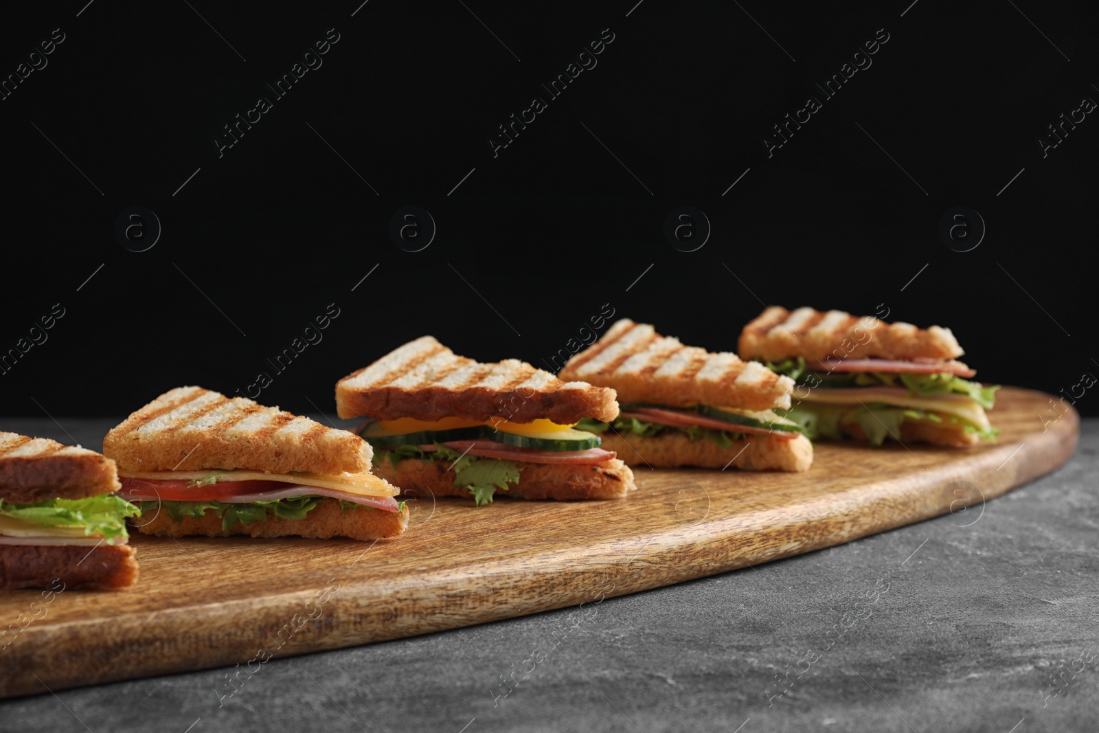 Photo of Tasty sandwiches with ham on grey table