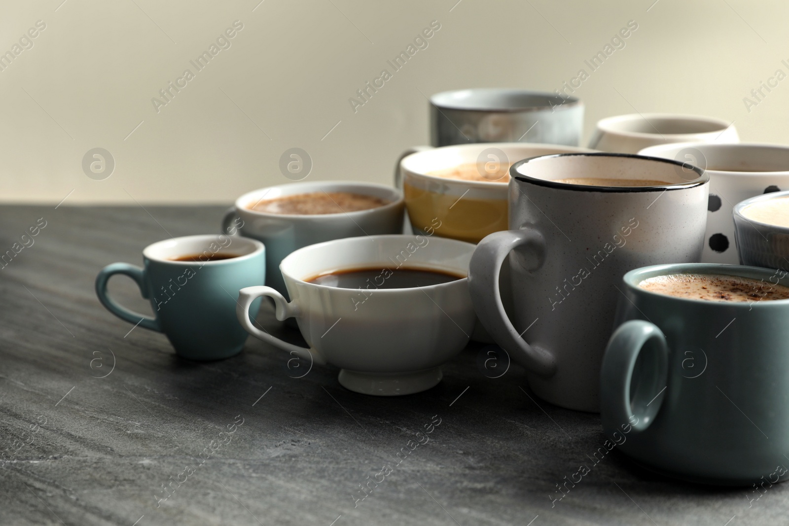 Photo of Many cups of different coffees on slate table