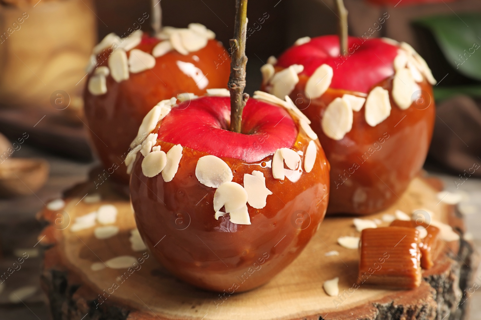 Photo of Delicious caramel apples on wooden serving board