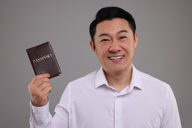 Photo of Immigration. Happy man with passport on grey background