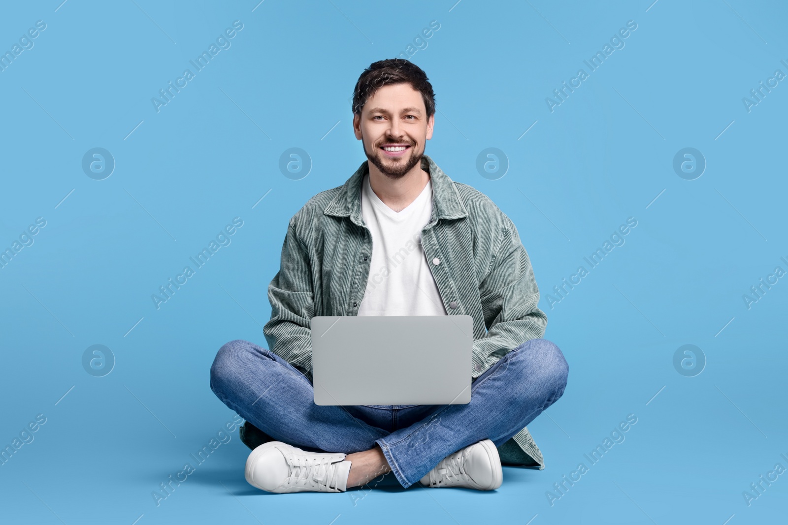 Photo of Happy man with laptop on light blue background