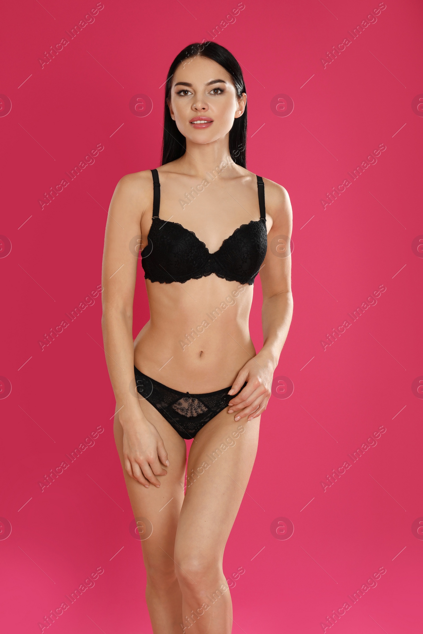 Photo of Beautiful young woman in black underwear on pink background