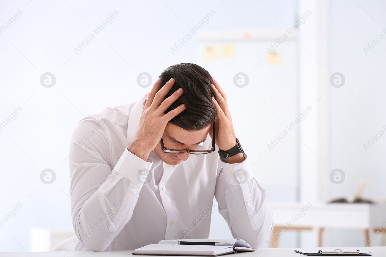 Photo of Stressed man at white table in office