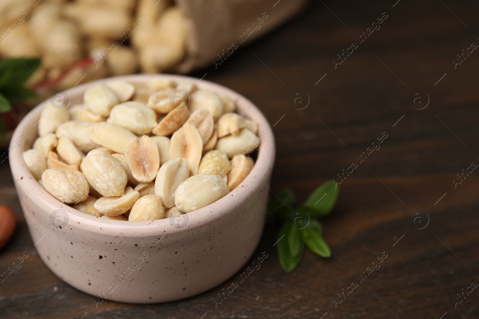 Photo of Fresh peeled peanuts in bowl on wooden table, closeup. Space for text