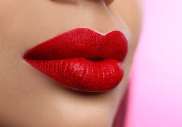 Image of Woman with beautiful perfect lips after permanent makeup procedure on pink background, closeup