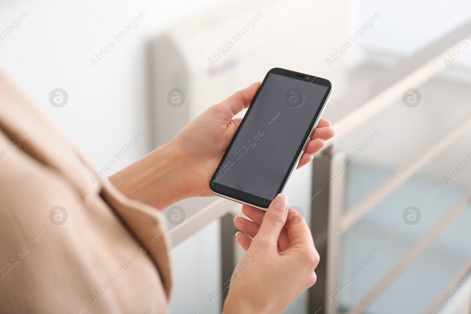 Photo of Young woman using modern smartphone indoors, closeup