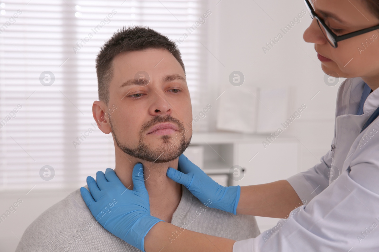 Photo of Doctor examining thyroid gland of patient in hospital