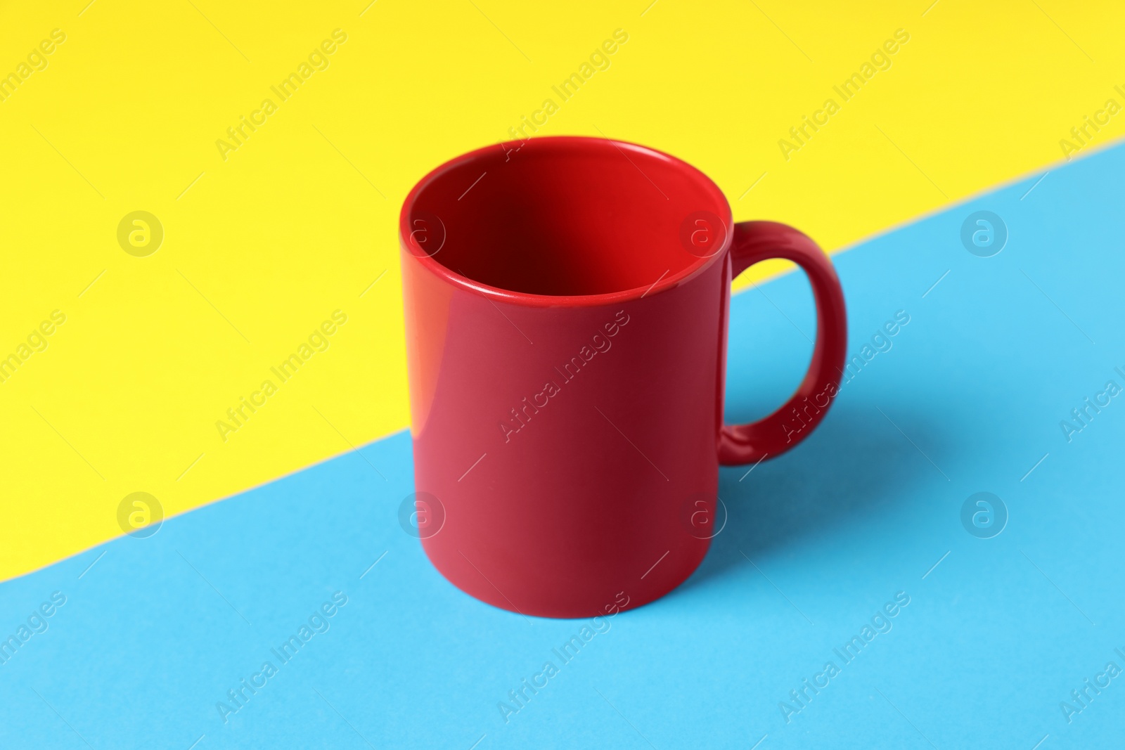 One red ceramic mug on color background Photo of One red ceramic mug on color background