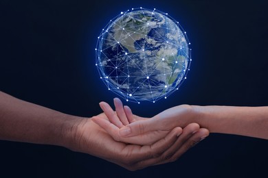 Image of Man and woman holding digital model of Earth on dark background, closeup