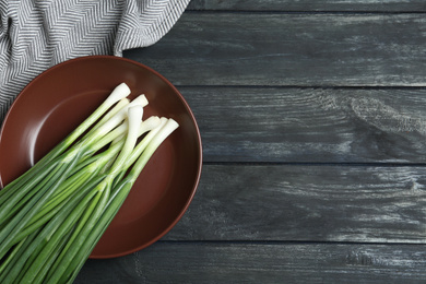 Photo of Fresh green spring onions on black wooden table, flat lay. Space for text